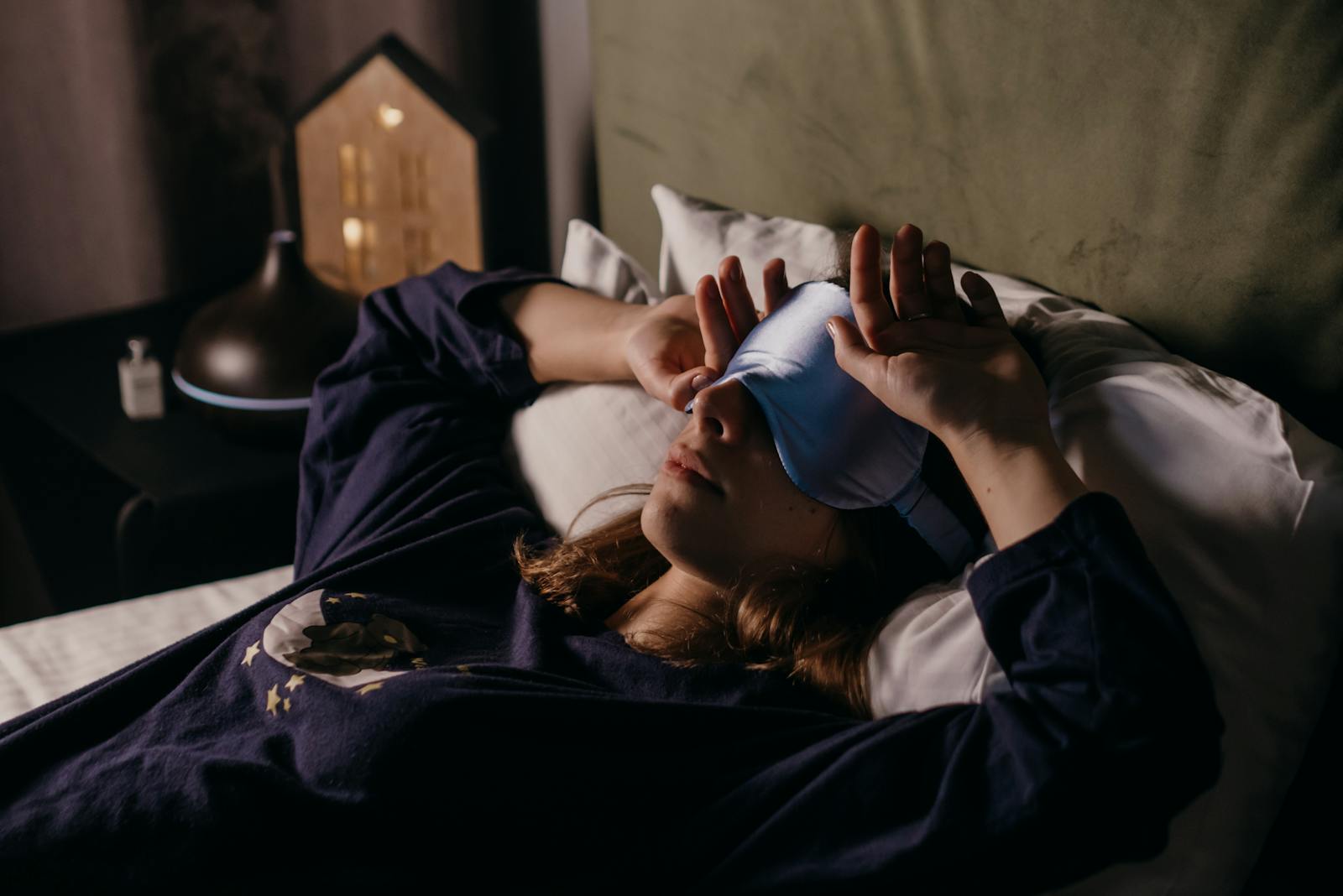 A woman in comfortable attire rests indoors wearing a sleep mask, exuding a cozy and peaceful mood.