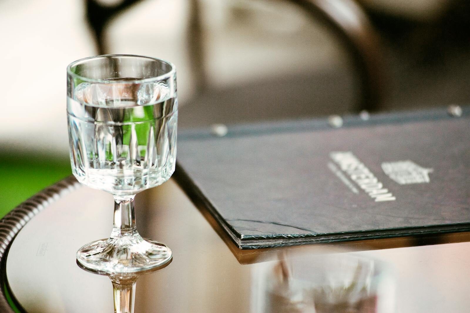 Crystal-clear glass of water beside a menu on a polished table, exuding a chic dining ambiance.