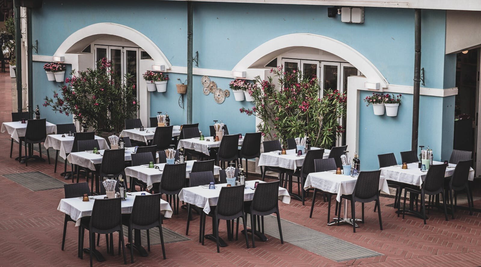 Cozy outdoor cafe with neatly arranged tables and a vibrant blue facade, perfect for dining.