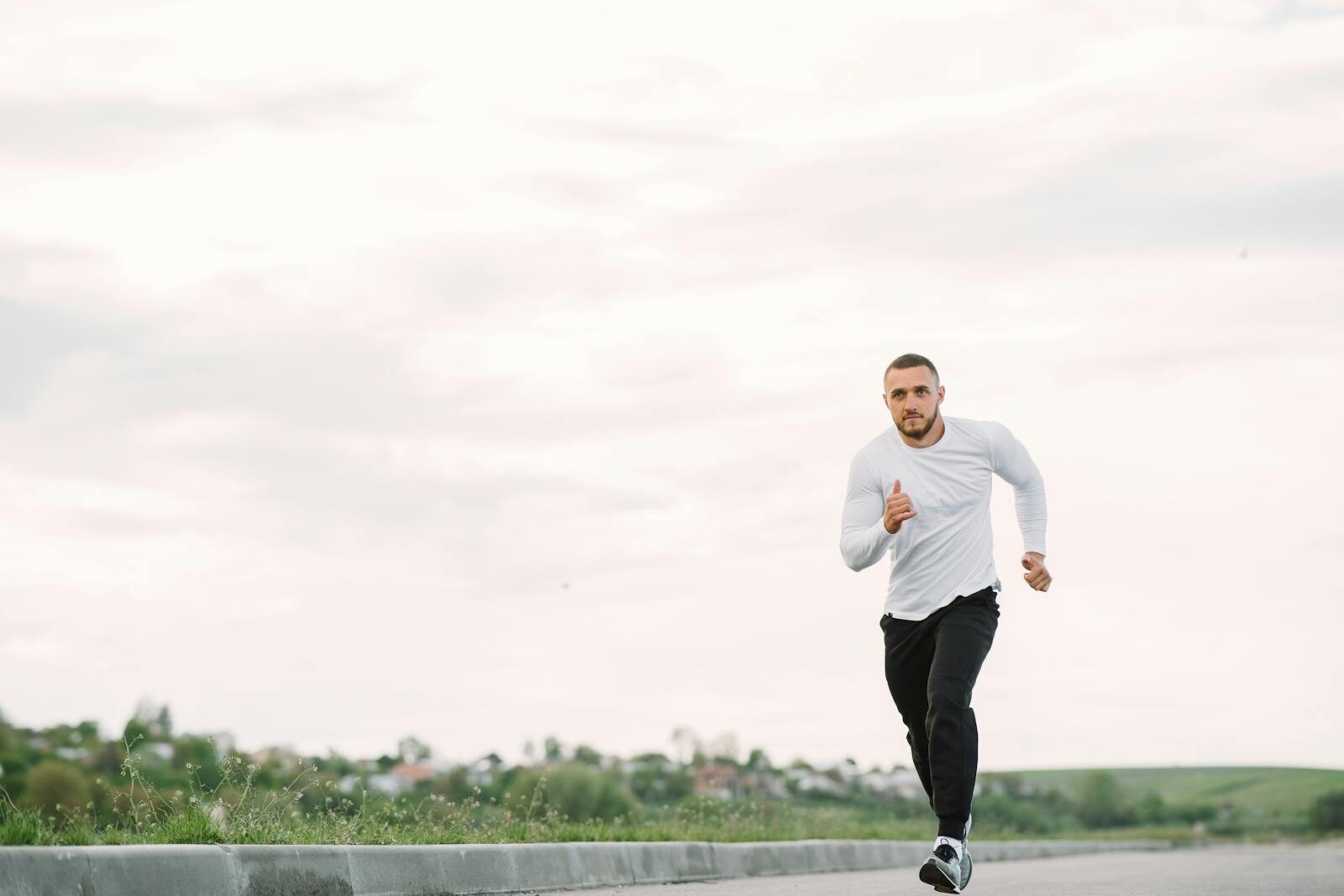 Adult man running on an empty road in casual sportswear, showcasing fitness and healthy lifestyle.