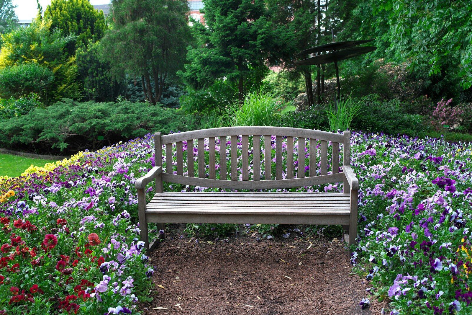 Bench sits peacefully amidst colorful flowers in a garden.